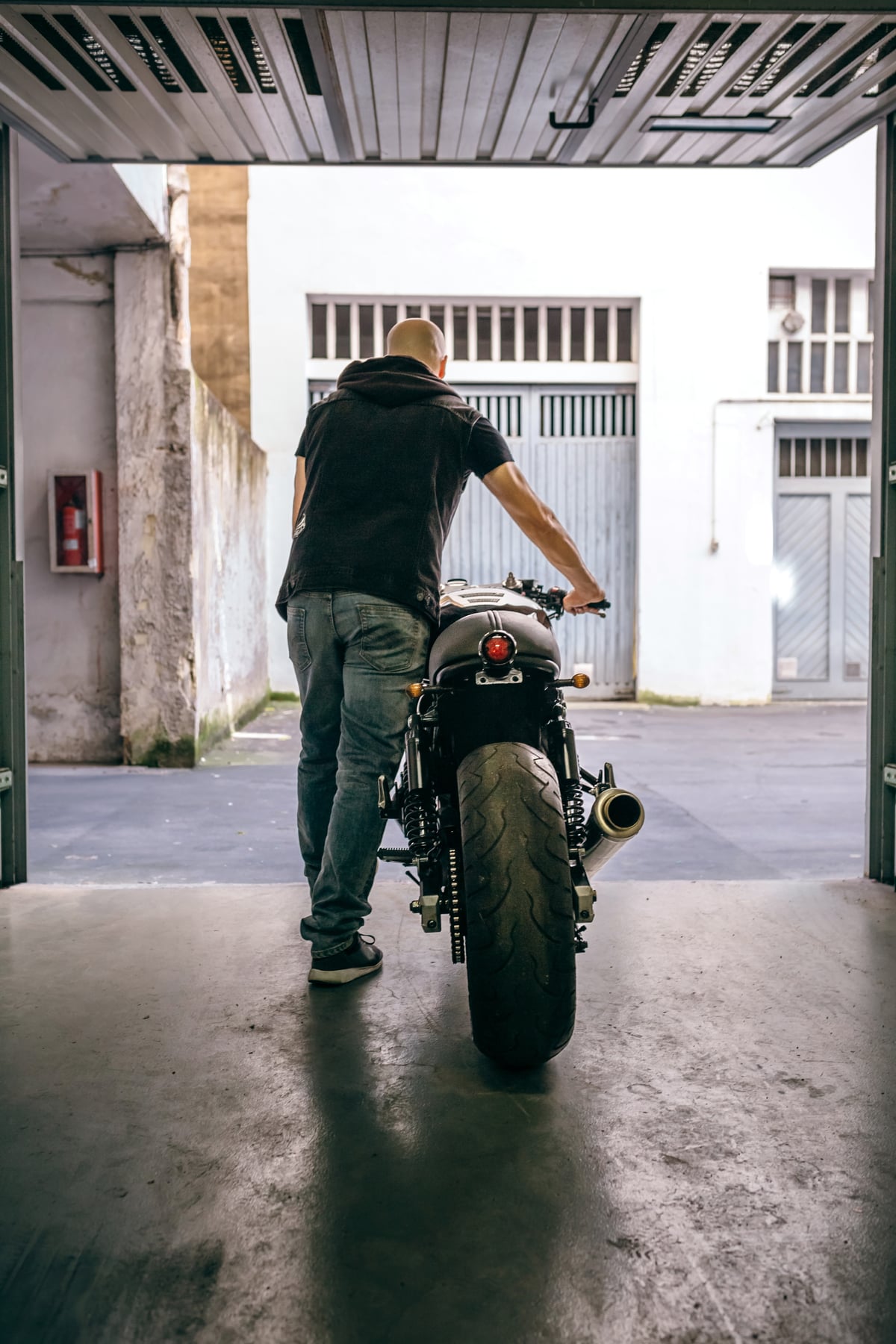 Person schiebt ein Motorrad aus einer Garage